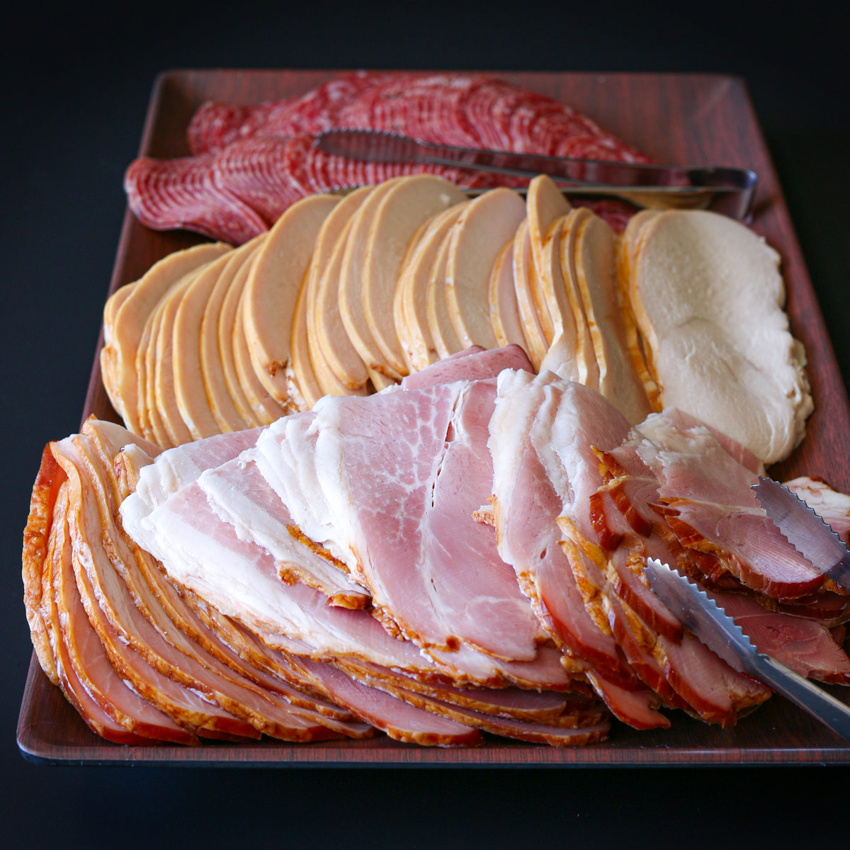 meat platter with forked tongs on side.