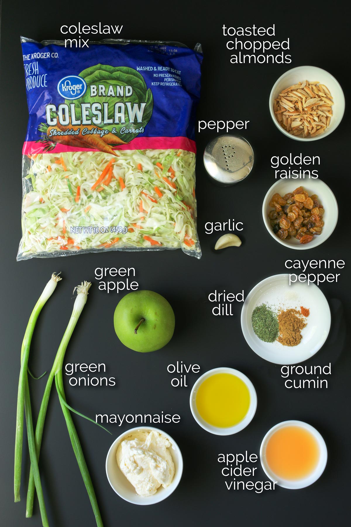 coleslaw ingredients laid out on black table.