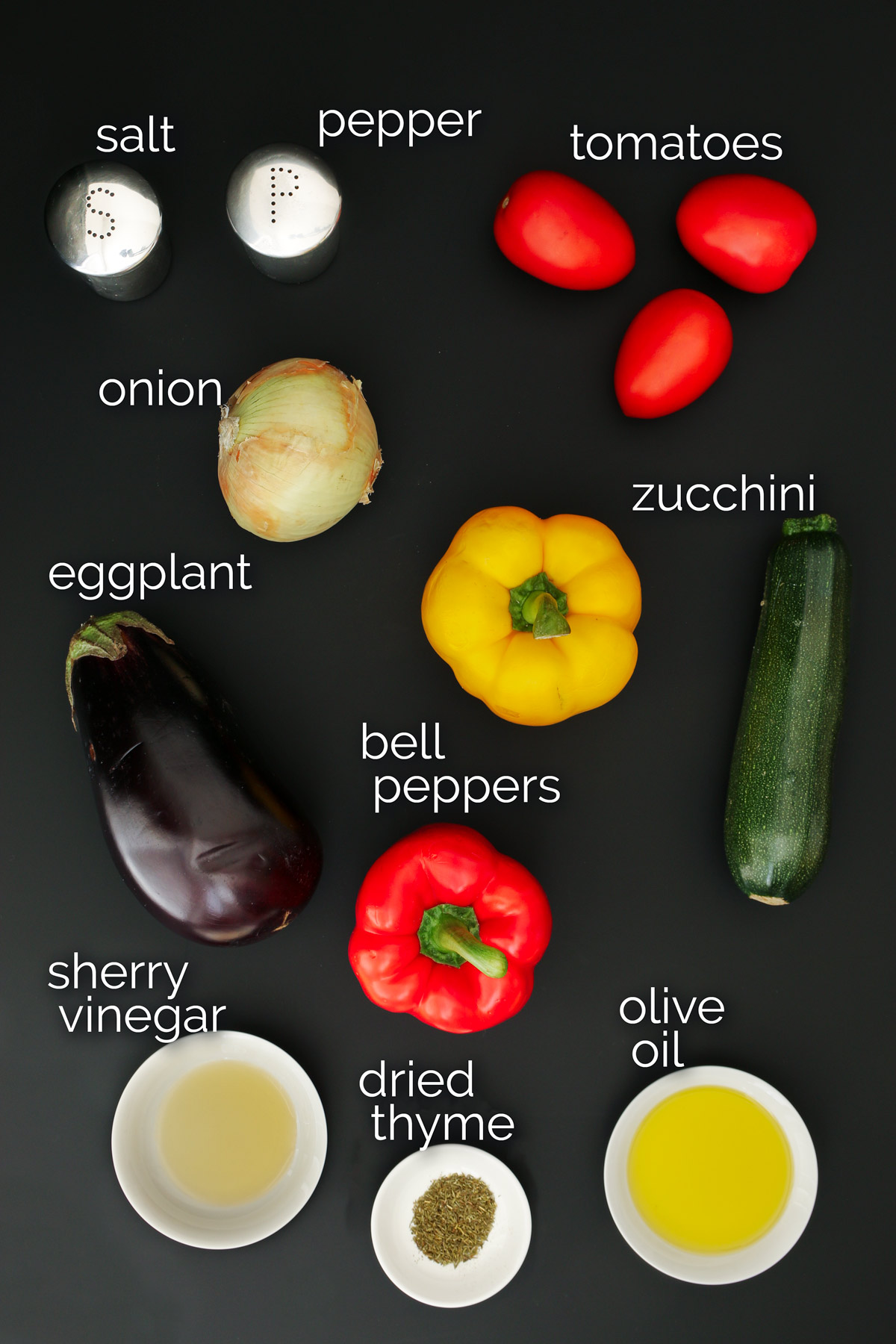 vegetables and other escalivada ingredients laid out on a black table top.