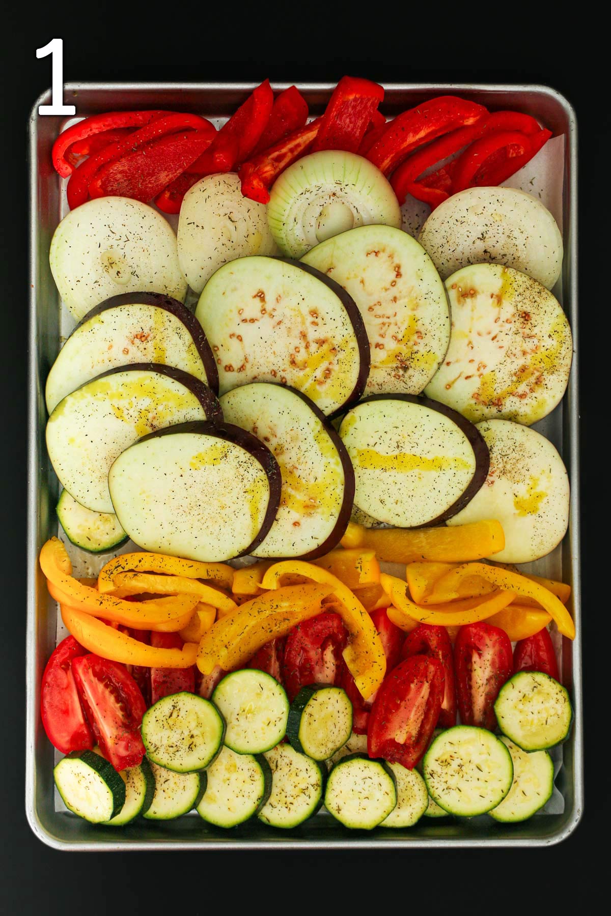 escalivada vegetables on rimmed baking sheet prepped for oven.