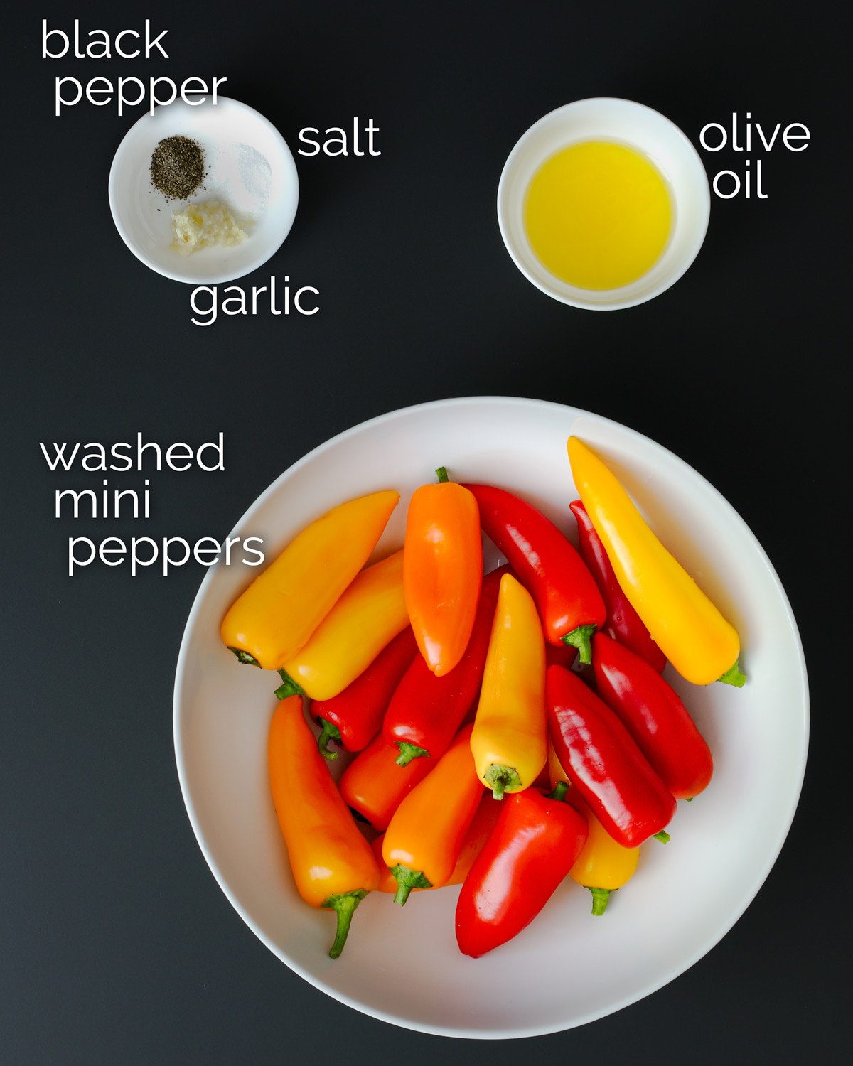 ingredients for grilled peppers laid out on black table.