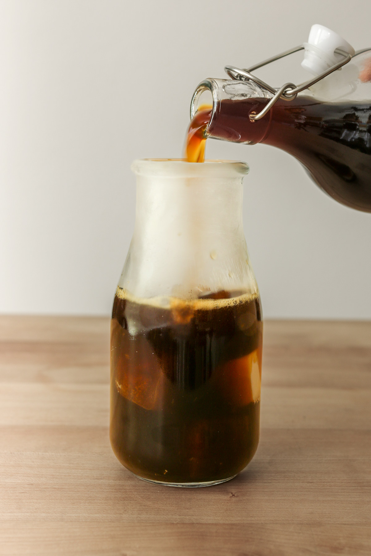 pouring cold brew concentrate into milk bottle from a long necked bottle.