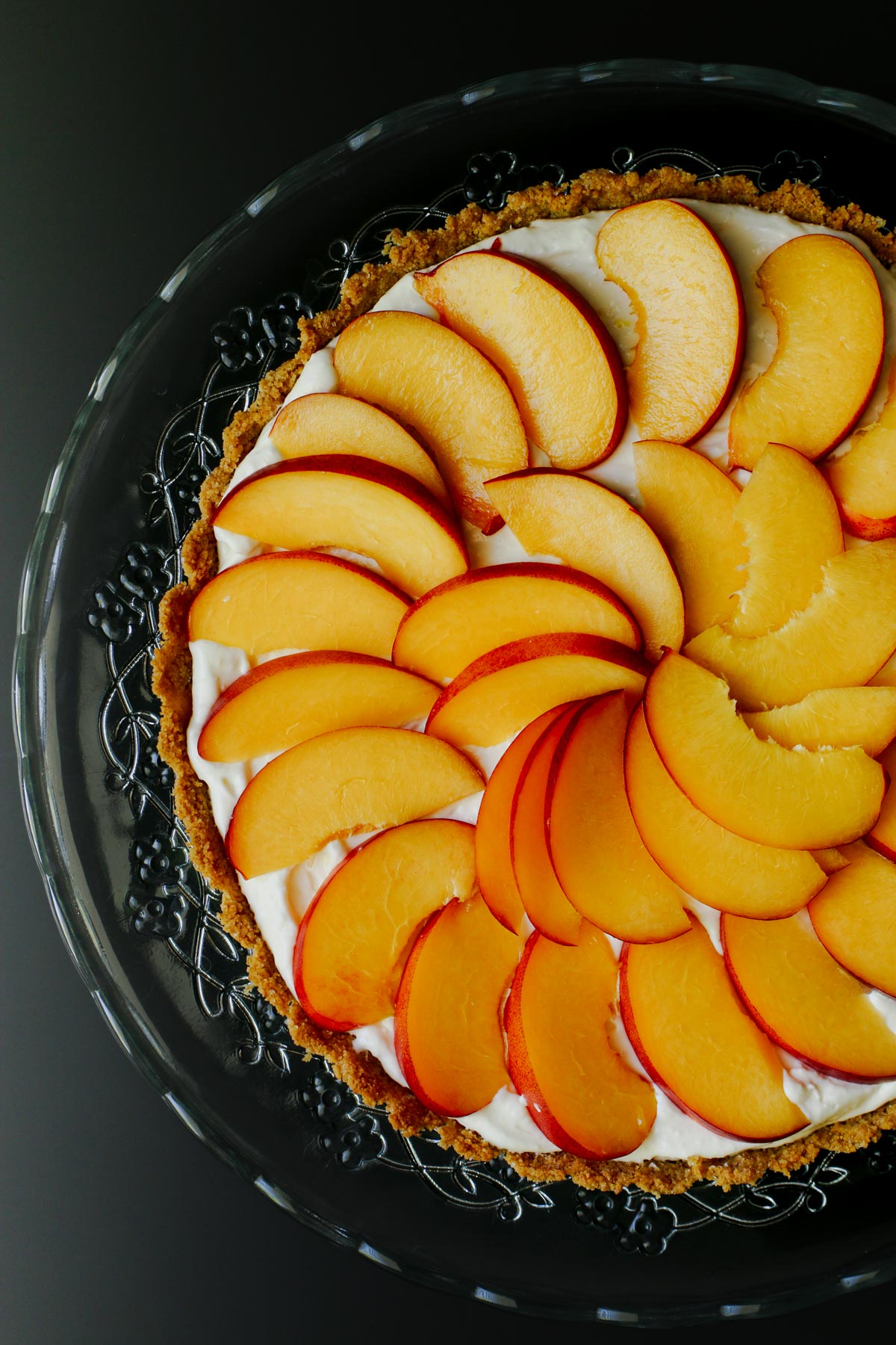 overhead close up of fresh nectarine pie on glass dessert stand.