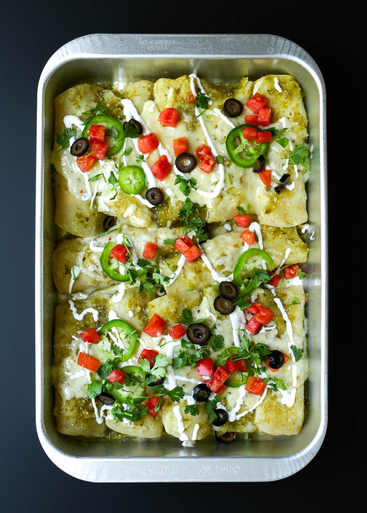 baked enchiladas topped with tomatoes, jalapenos, cilantro, and olives.
