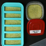 overhead shot of frozen pesto in souper cubes as well as in small plastic box.