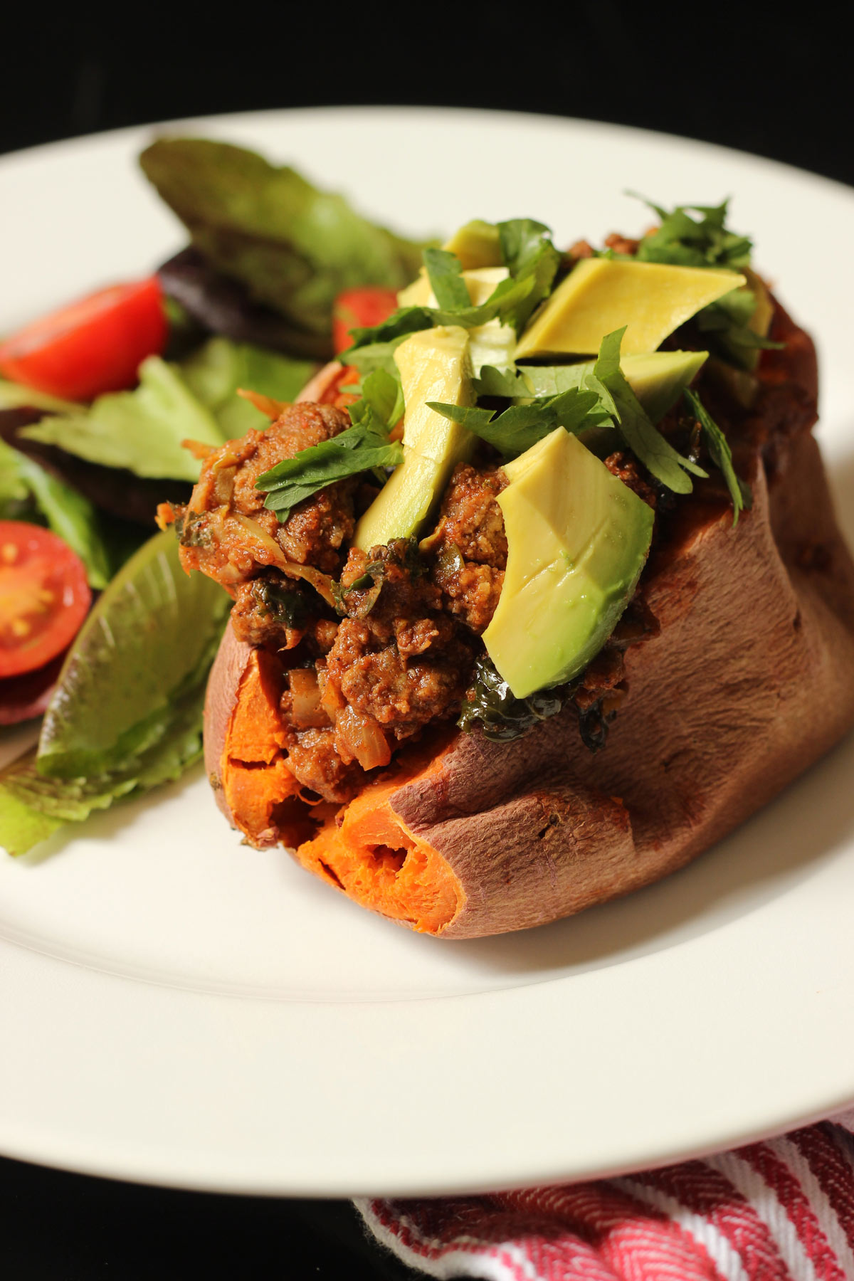 chili stuffed sweet potato and salad on dinner plate.