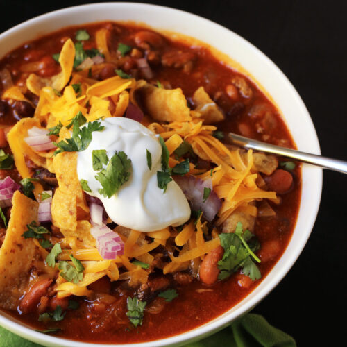 chili with toppings in white bowl.
