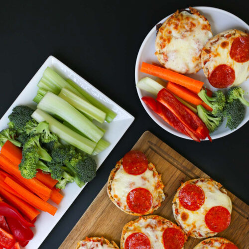 veggie platter alongside platter of mini pizzas with a plate dished up.