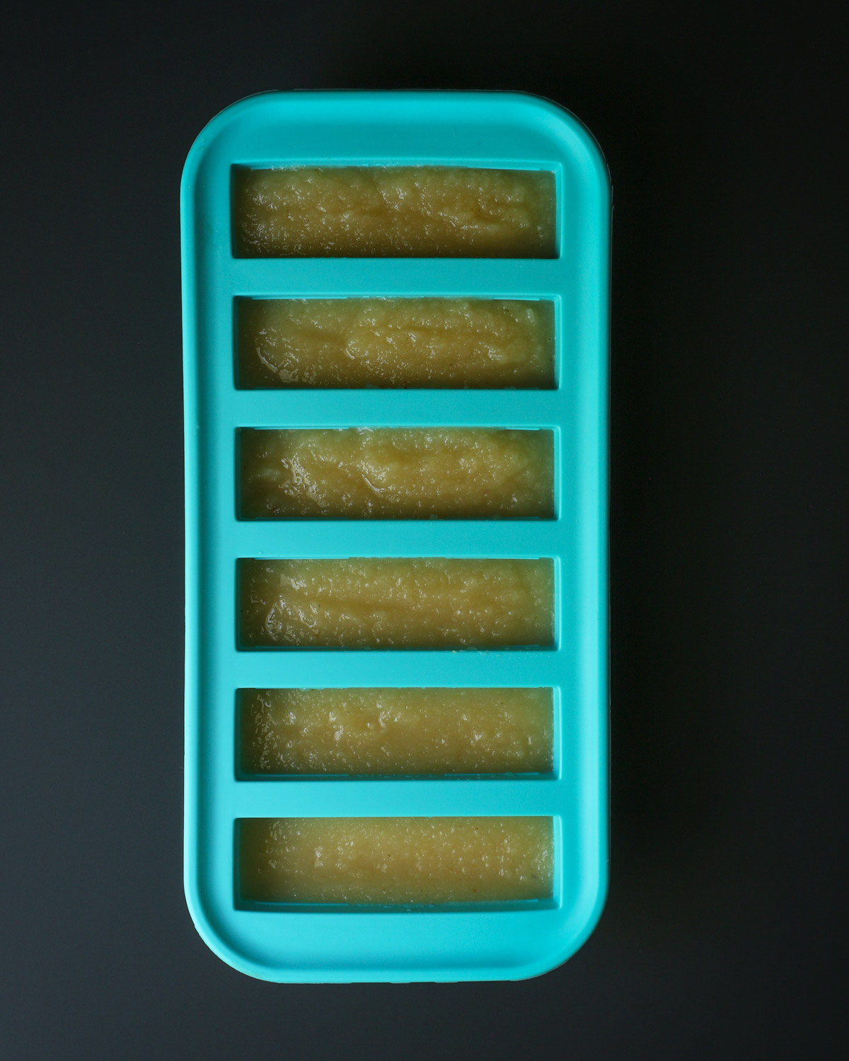 applesauce in teal souper cube tray on black table.