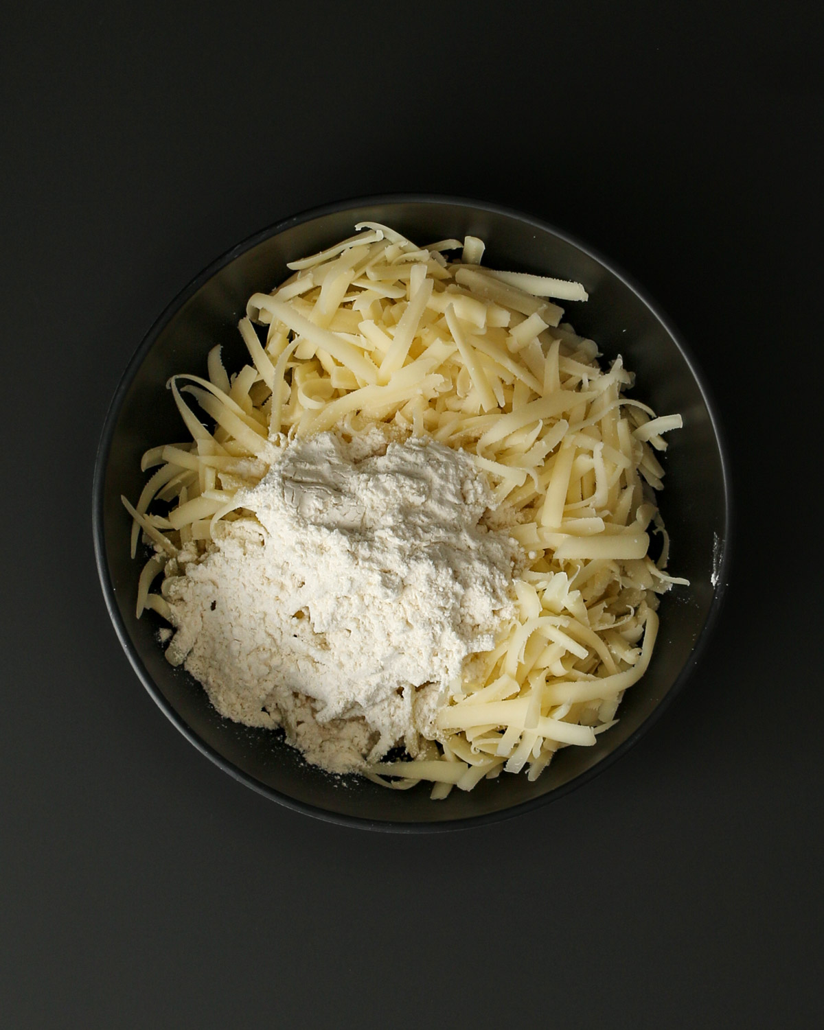 black bowl with cheese and flour.