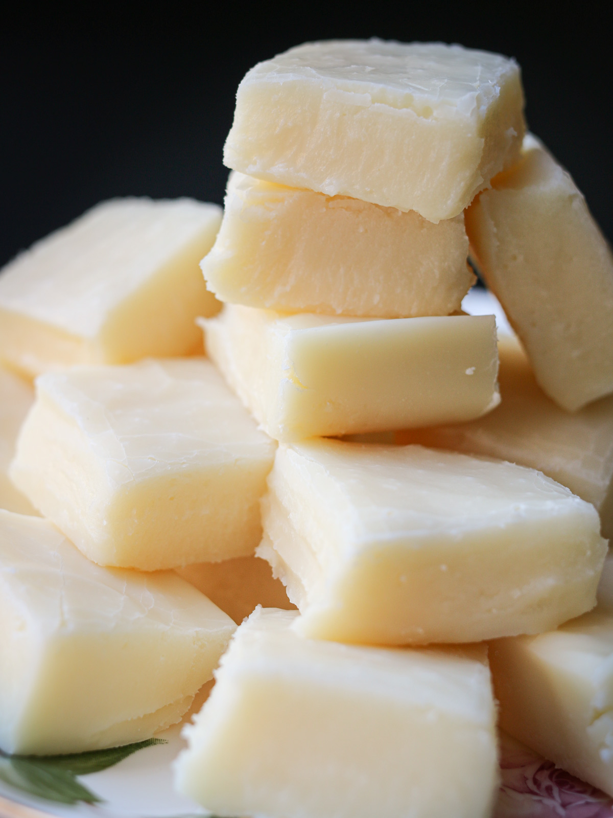 stack of white chocolate fudge with a black background.