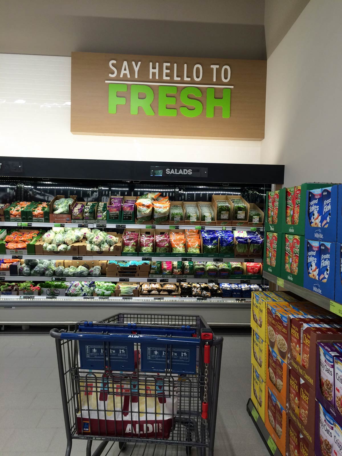 produce aisle of aldi with a cart with empty bags in it.