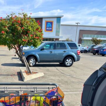 aldi storefront with parked cars in foreground.