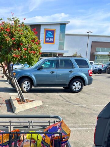aldi storefront with parked cars in foreground.