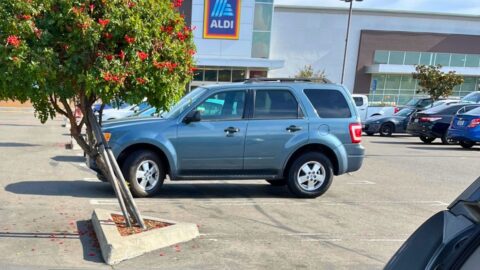 aldi storefront with parked cars in foreground.