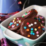 close up of dish of chocolate dipped oreos with confetti sprinkles.