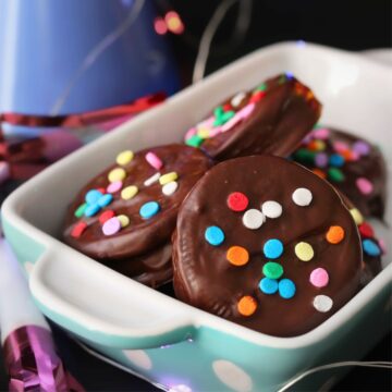 close up of dish of chocolate dipped oreos with confetti sprinkles.
