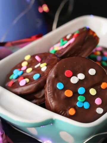 close up of dish of chocolate dipped oreos with confetti sprinkles.