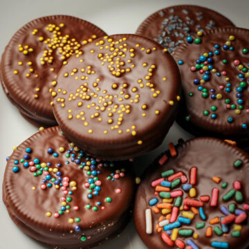 white plate with chocolate-dipped Oreos with colorful sprinkles.