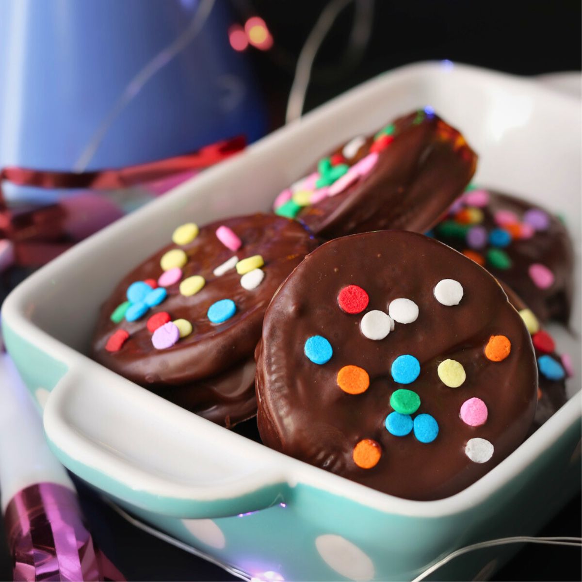 close up of dish of chocolate dipped oreos with confetti sprinkles.