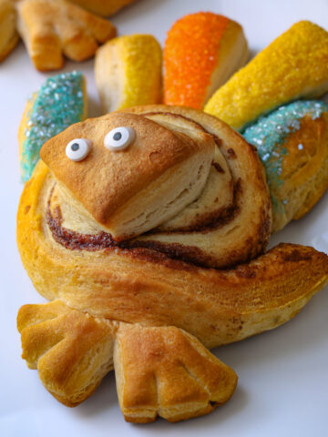 baked cinnamon roll turkey with candy eyes on white tray.