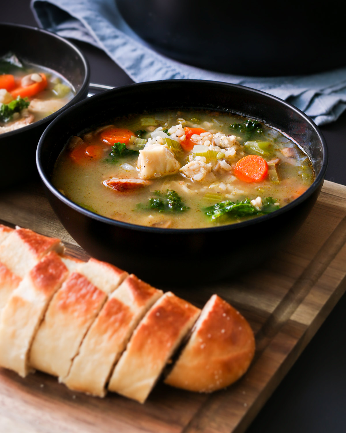 bowls of turkey soup on wooden board with sliced bread.