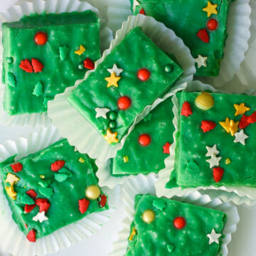 Christmas Fudge squares in white muffin papers on a white plate.