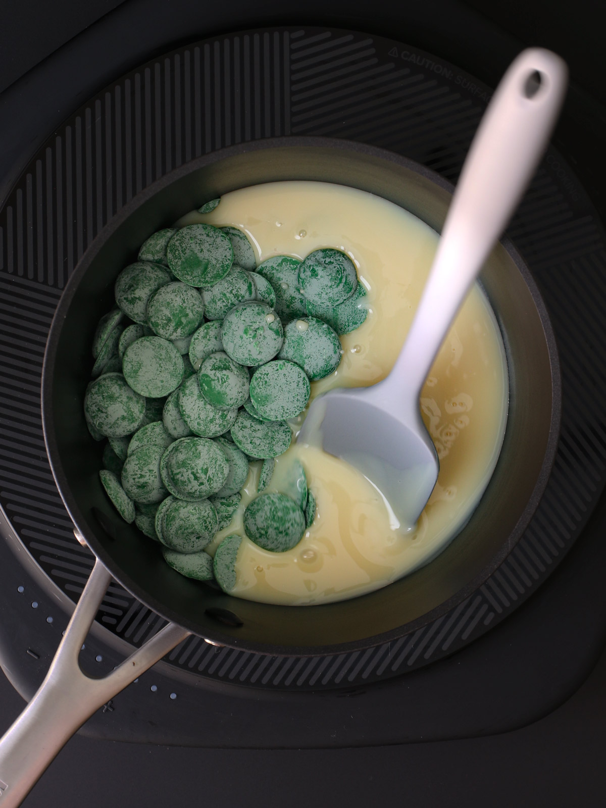 milk and candy melts in saucepan with grey spatula.