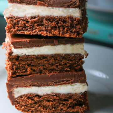 stack of chocolate mint brownies on a plate near a book.