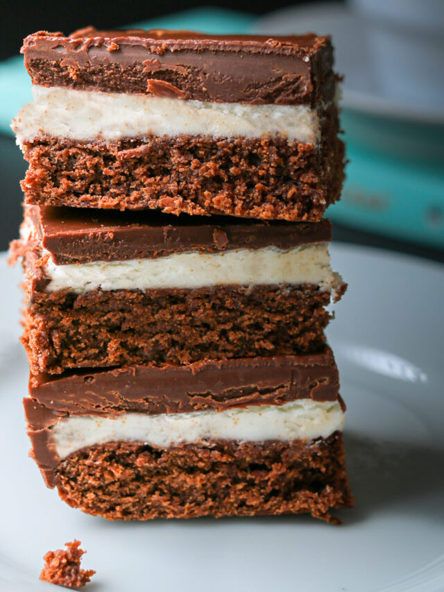 stack of chocolate mint brownies on a plate near a book.