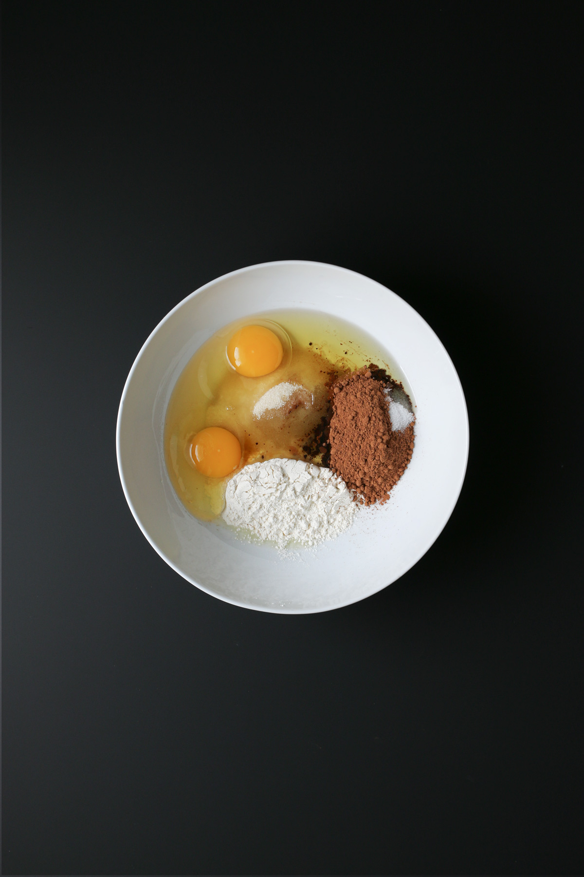brownie ingredients in a white bowl on a black table.