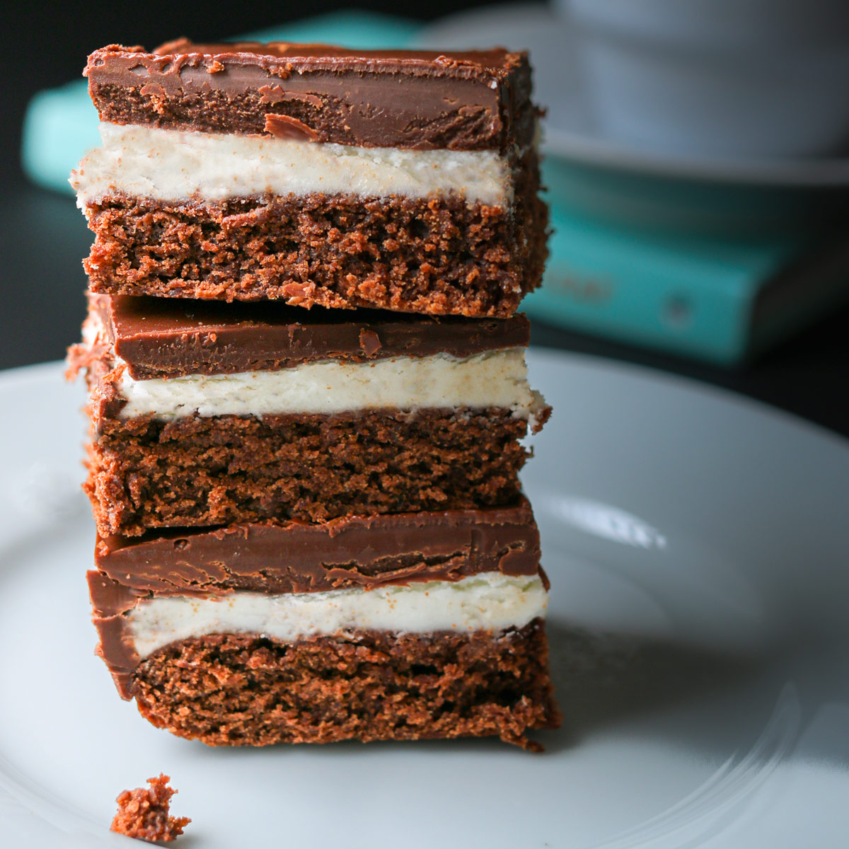 stack of chocolate mint brownies on a plate near a book.