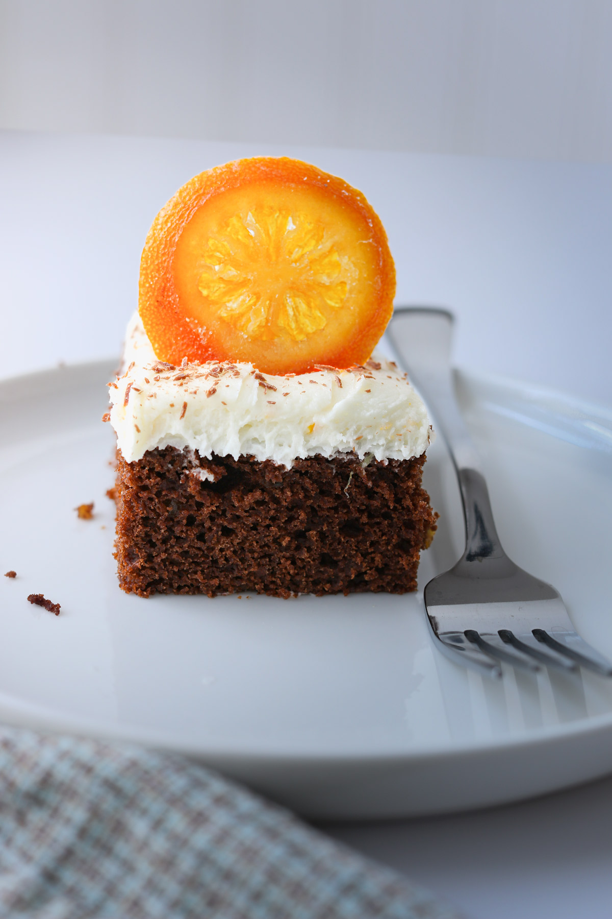 white plate with square of cake topped with candied orange slice.