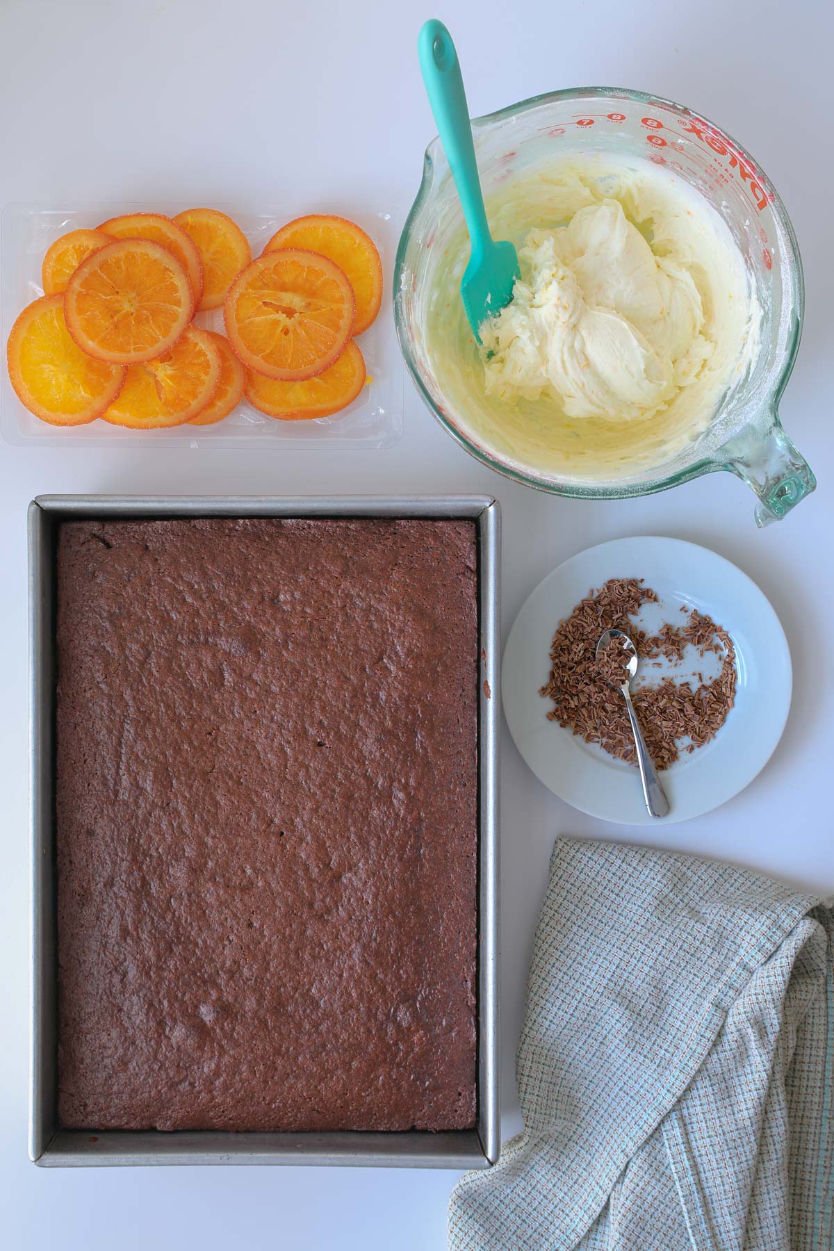 baked cake, bowl of frosting, and garnishes.
