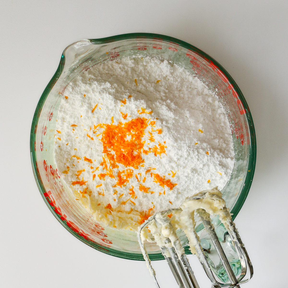 adding powdered sugar, salt, and orange zest to the mixing bowl.