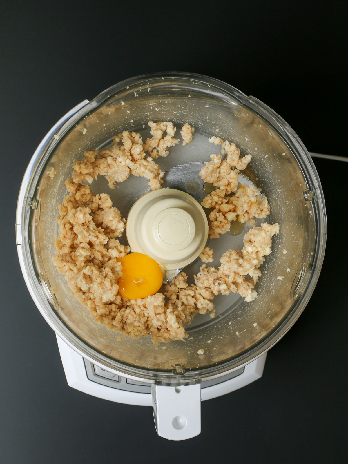 adding egg yolk and extract to butter mixture in food processor.