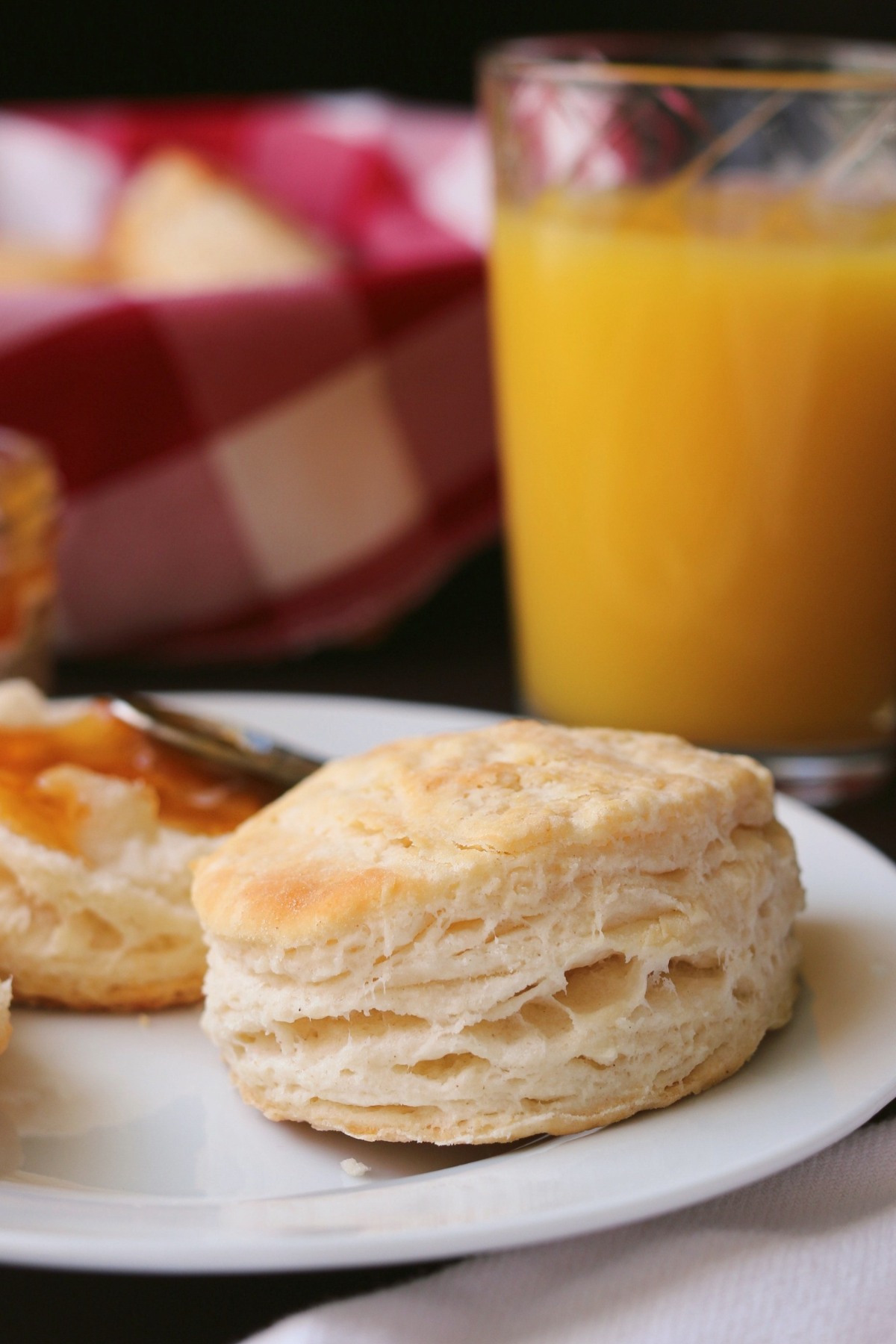 self-rising flour biscuit on plate with orange juice glass in background.