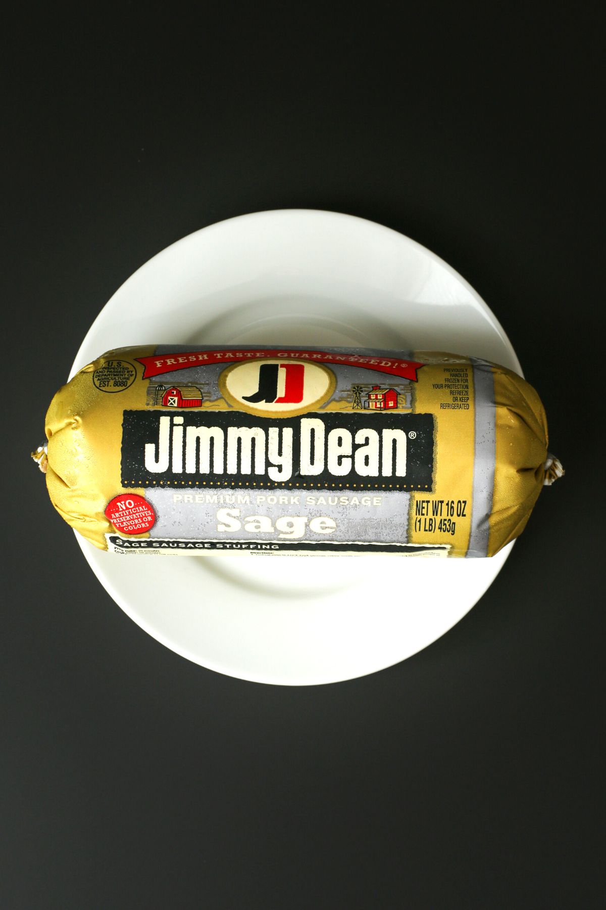 tube of Jimmy Dean sage sausage on a plate on a black table.