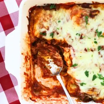 ravioli casserole with a portion removed and a saucy spoon.