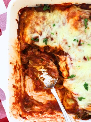 ravioli casserole with a portion removed and a saucy spoon.