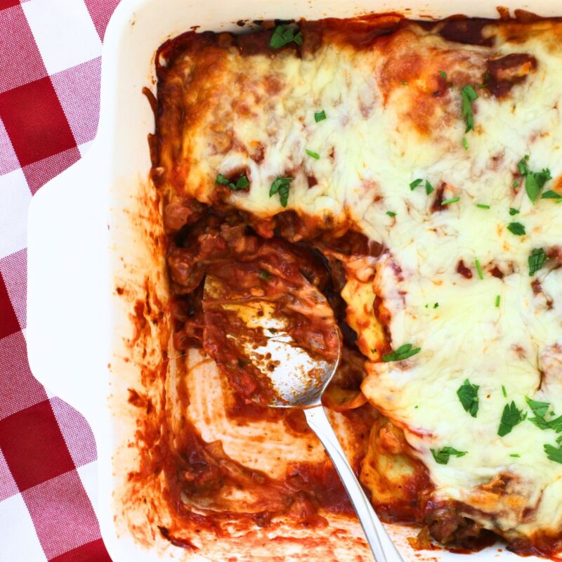 ravioli casserole with a portion removed and a saucy spoon.