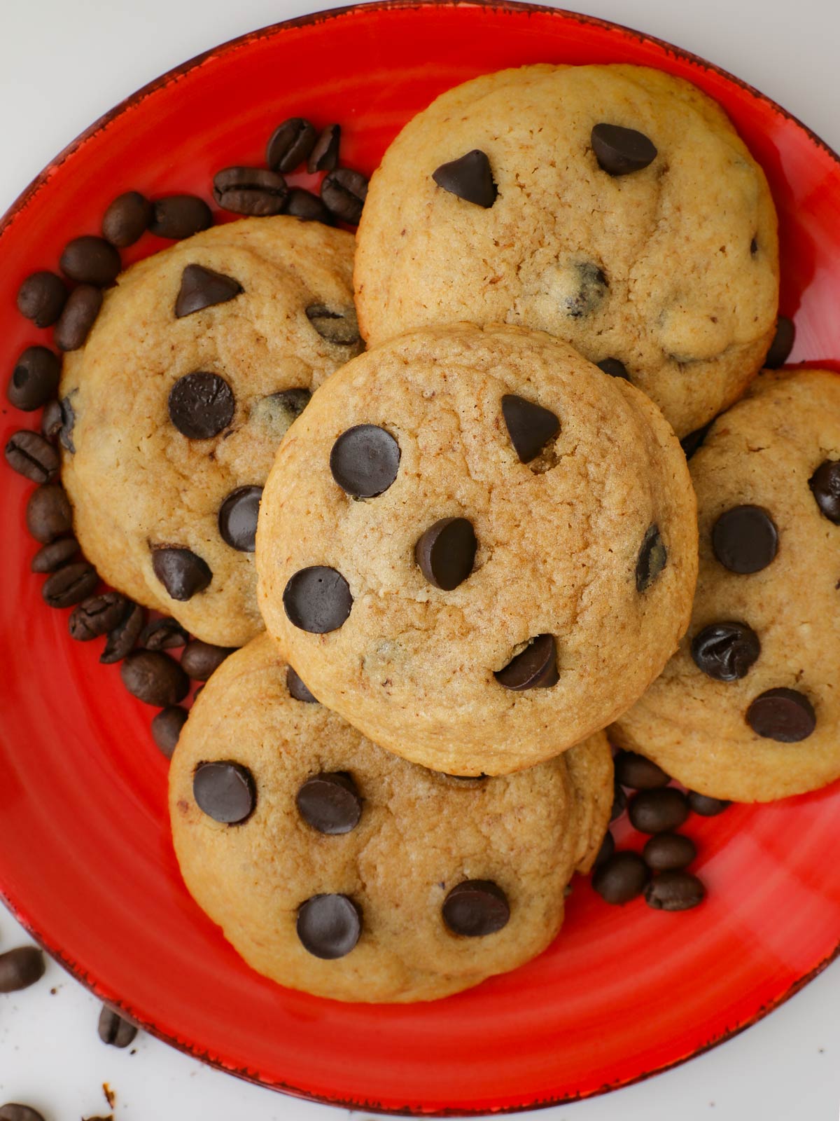coffee cookies piled on red plate with coffee beans.