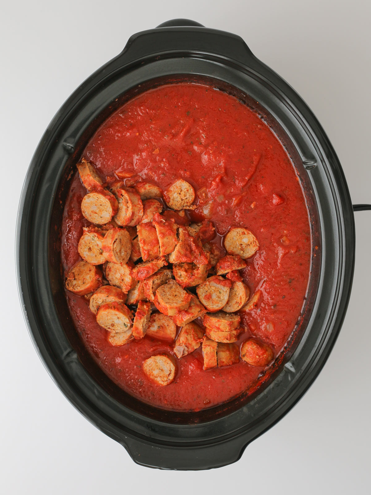 adding sausage slices back to sauce in the pot.