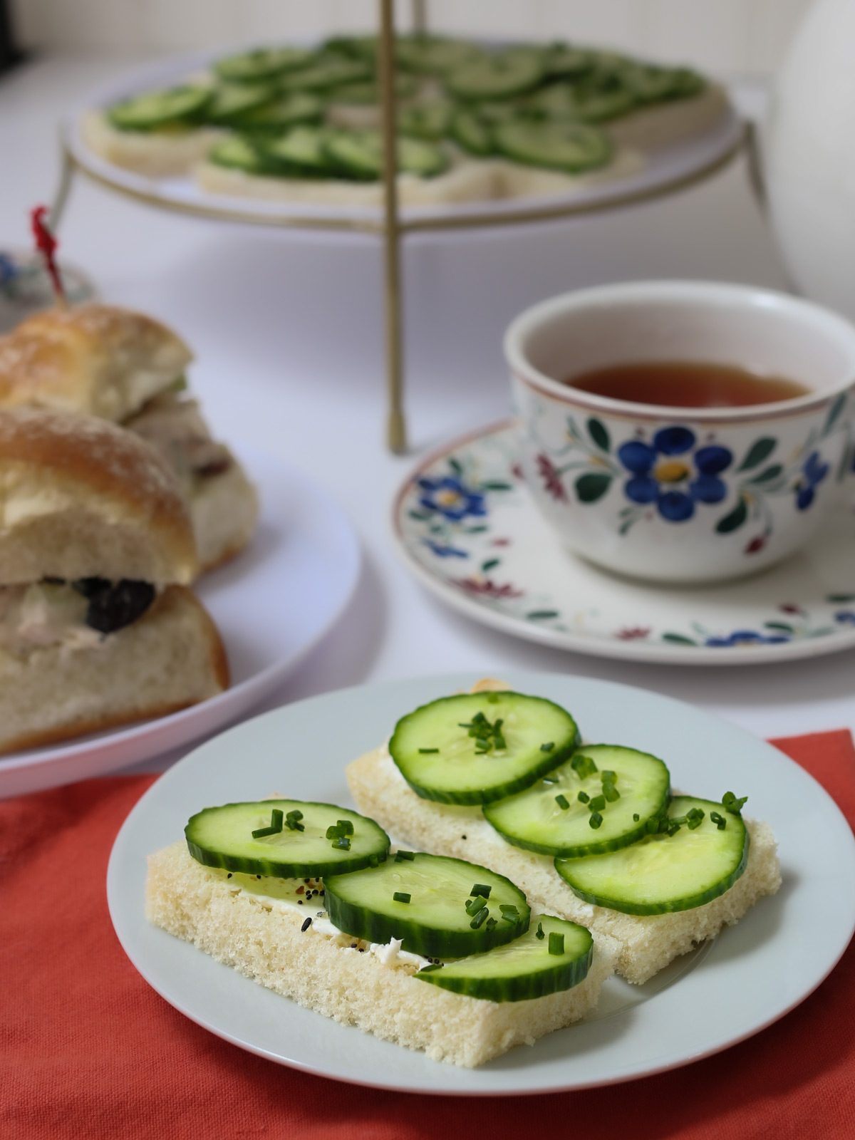 plate of cucumber sandwiches near tea cup and saucer on tea table.