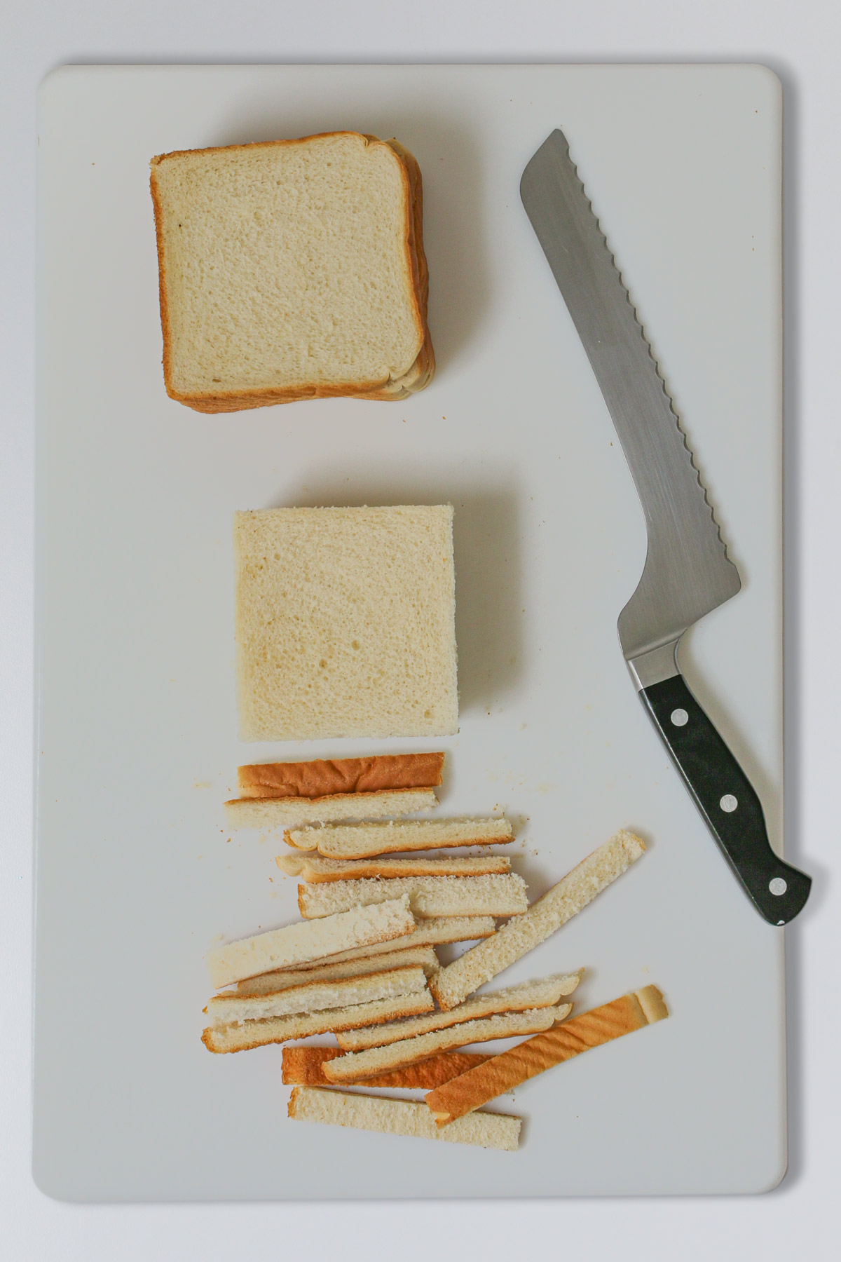 bread on cutting board with bread knife, cutting off crusts.