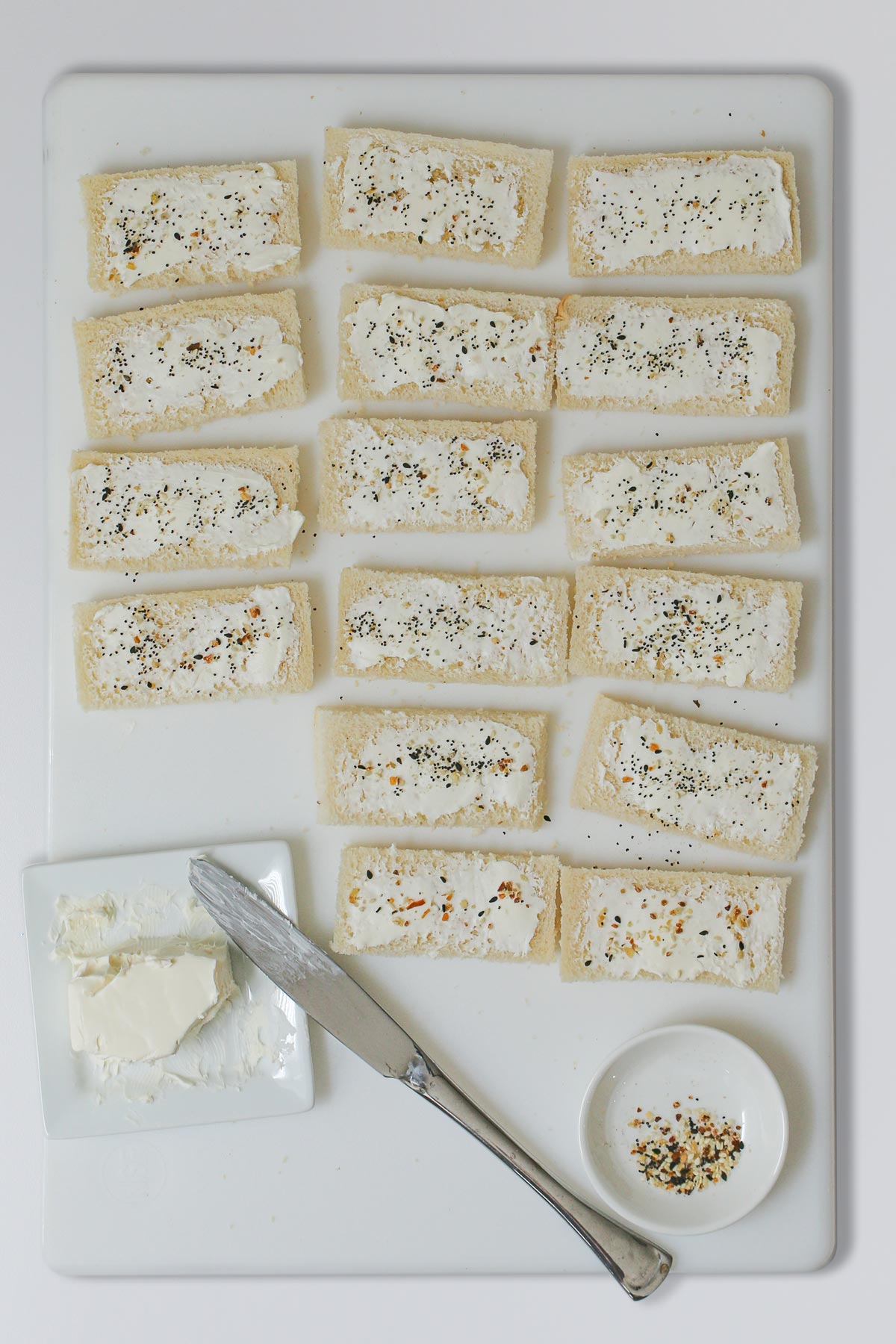 cream cheese spread on bread slices on board.