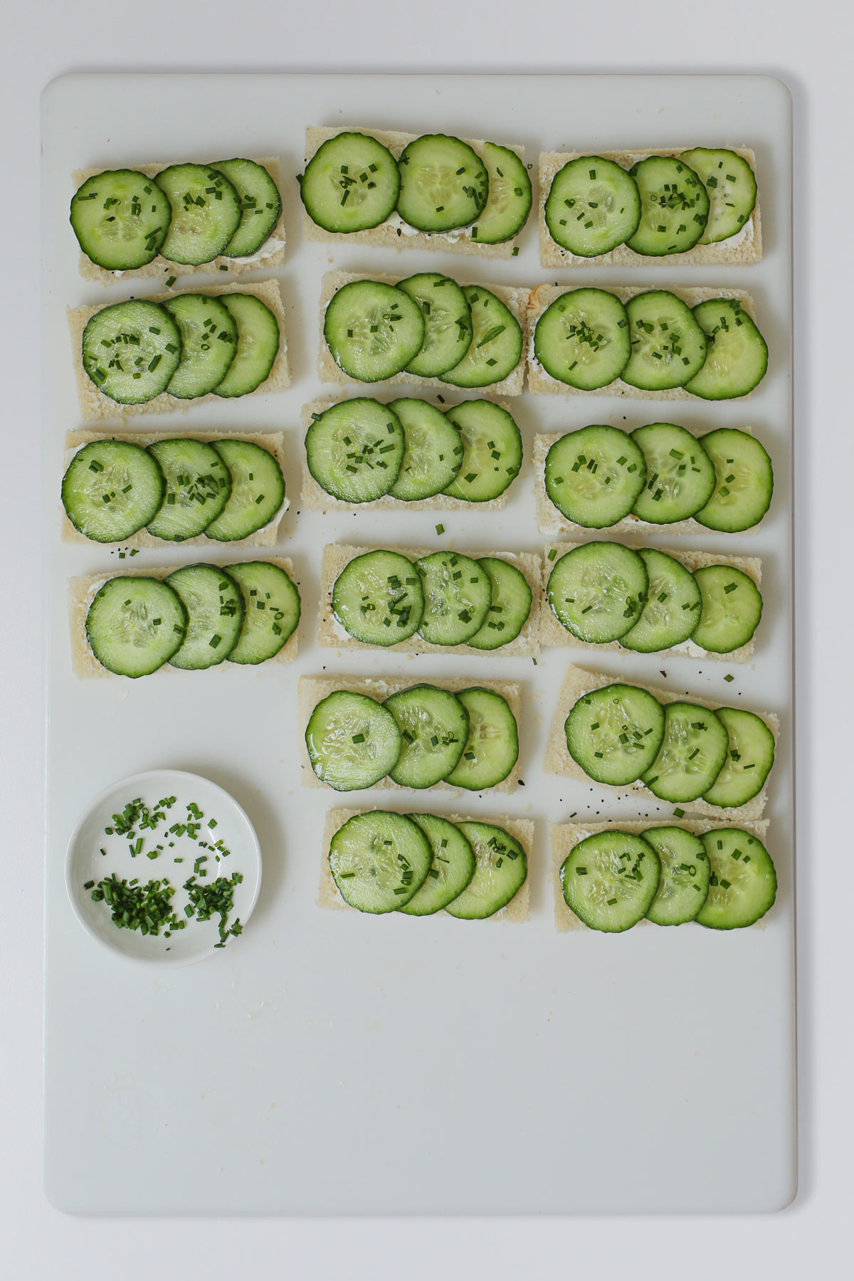 cucumber slices laid on bread strips and topped with chives.