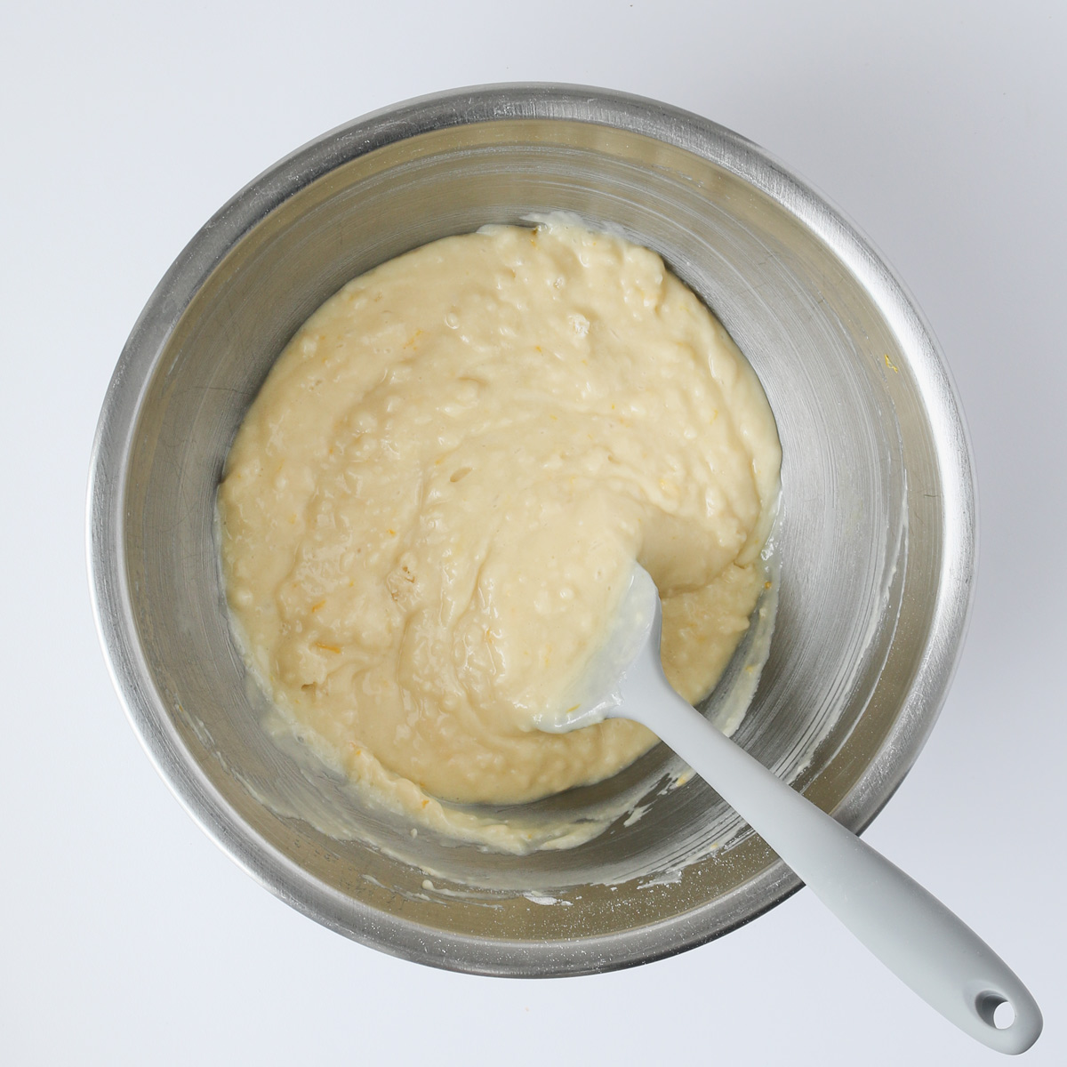 gray spatula mixing the cake batter in silver bowl.