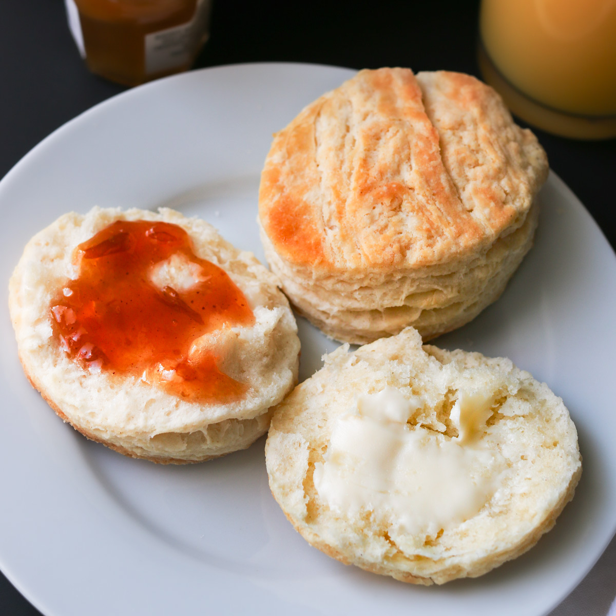 split biscuit on plate, with butter and jam.