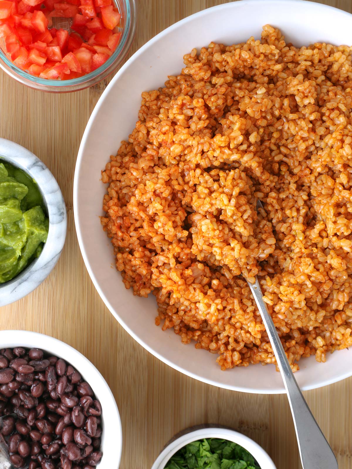 overhead shot of table with a bowl of Spanish brown rice and taco toppings.